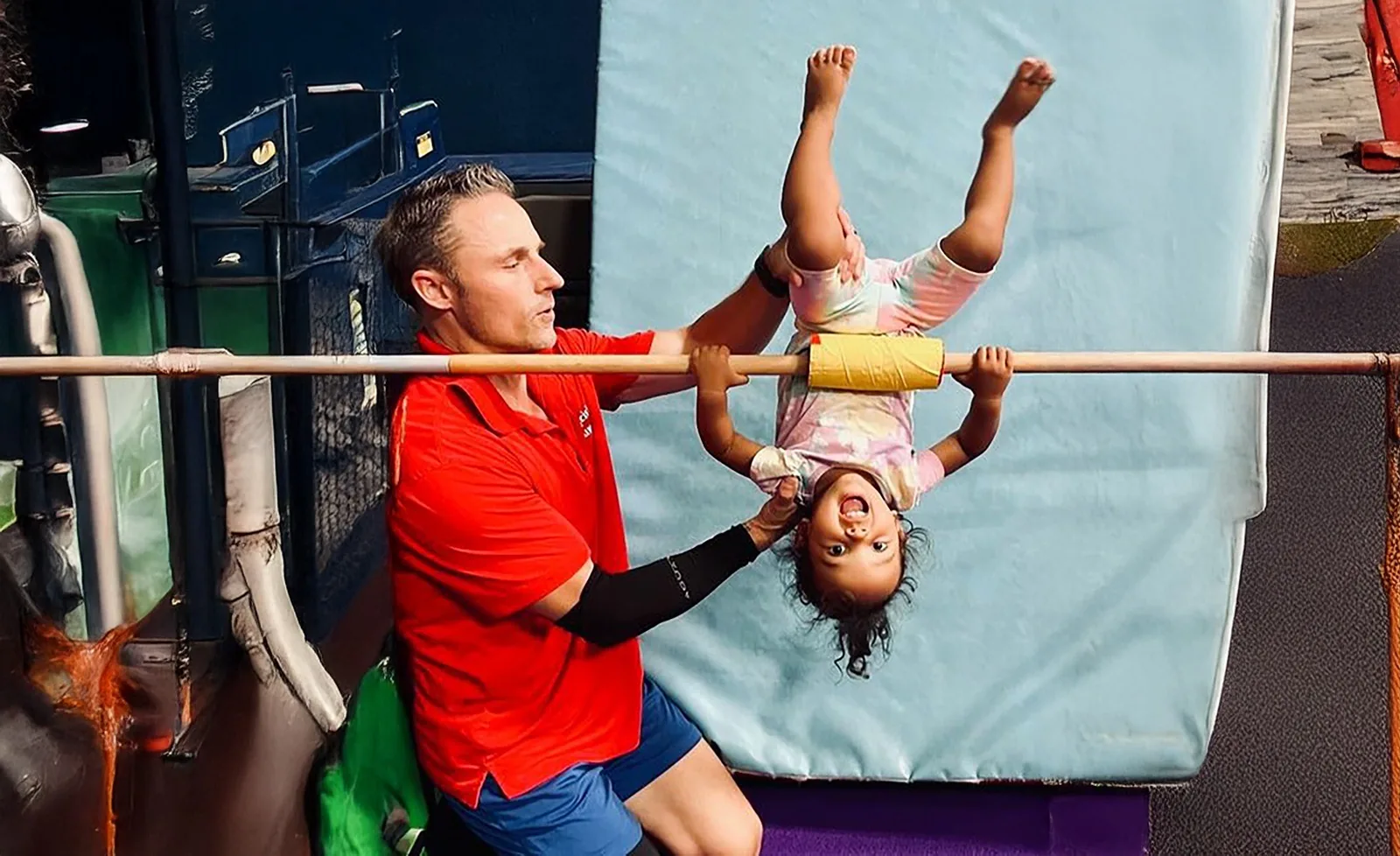 A coach spotting a young gymnast on bars