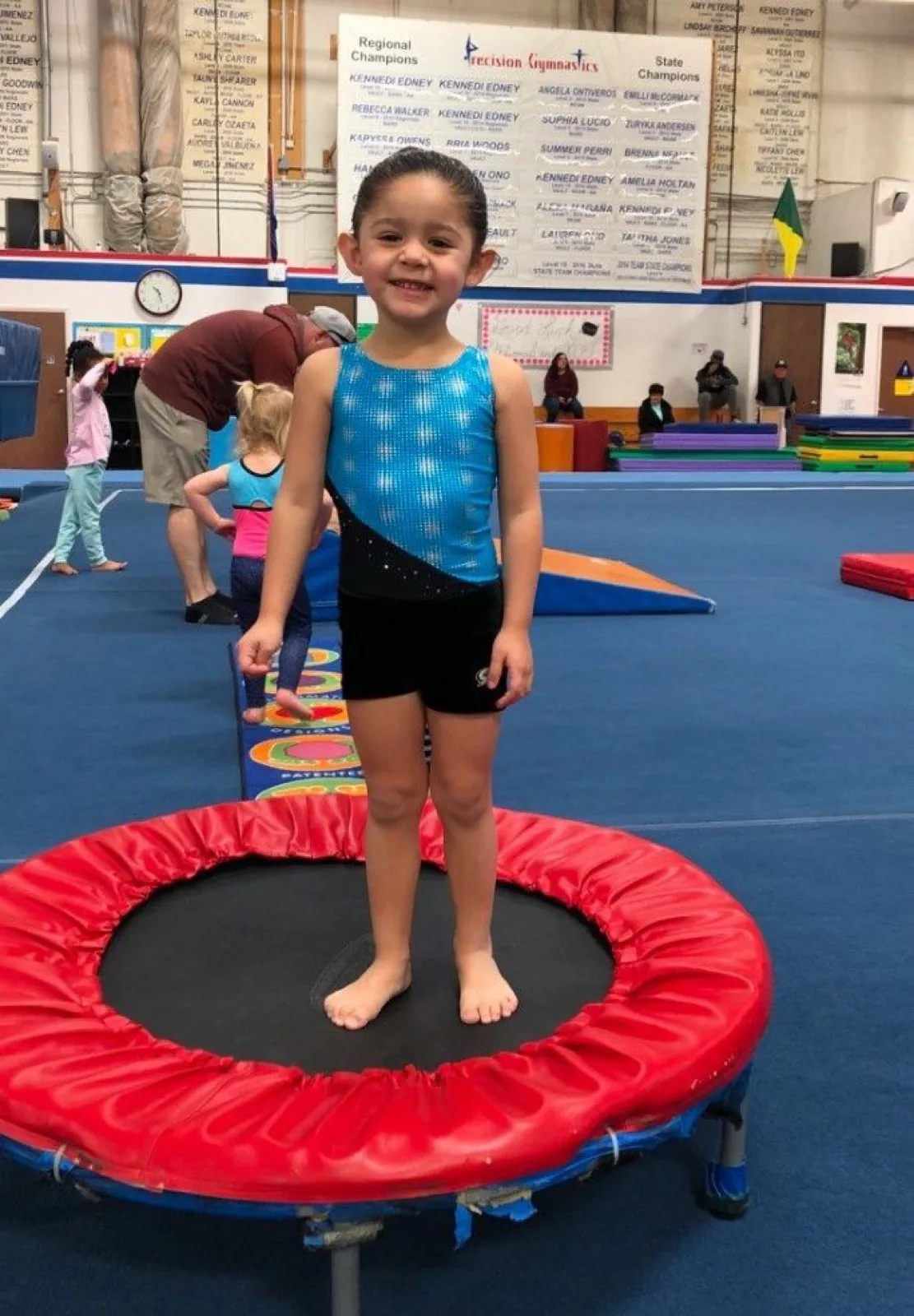 A preschooler standing on a small red trampoline